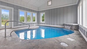 An indoor swimming pool with a clear view of the outdoors through large windows. - Mountain View Splash - Indoor Pool Hot Tub Game Room Stunning Smoky Mountain Views (Sevierville)