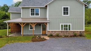 A two-story house with a covered porch, a stone foundation, and a sloped roof. - Mountain View Splash - Indoor Pool Hot Tub Game Room Stunning Smoky Mountain Views (Sevierville)