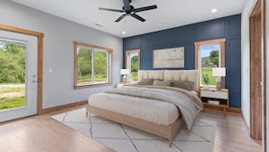 A bedroom with a large bed, two bedside tables, a ceiling fan, and a view of the outdoors. - Mountain View Splash - Indoor Pool Hot Tub Game Room Stunning Smoky Mountain Views (Sevierville)