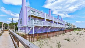 A multi-story beach house with a wooden deck and a sandy beach in the background. - Three Little Birds - Oceanfront Condo with Private Decks and Community Pools. Mu (Kure)