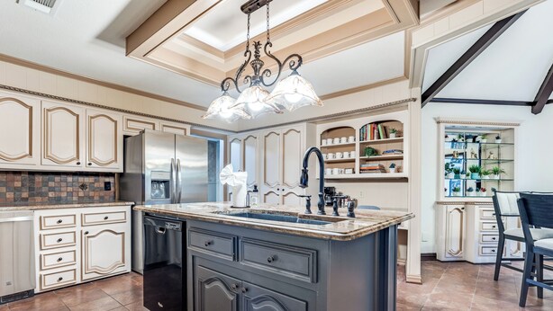 Una cocina amplia con una isla grande, electrodomésticos integrados y una lámpara decorativa.