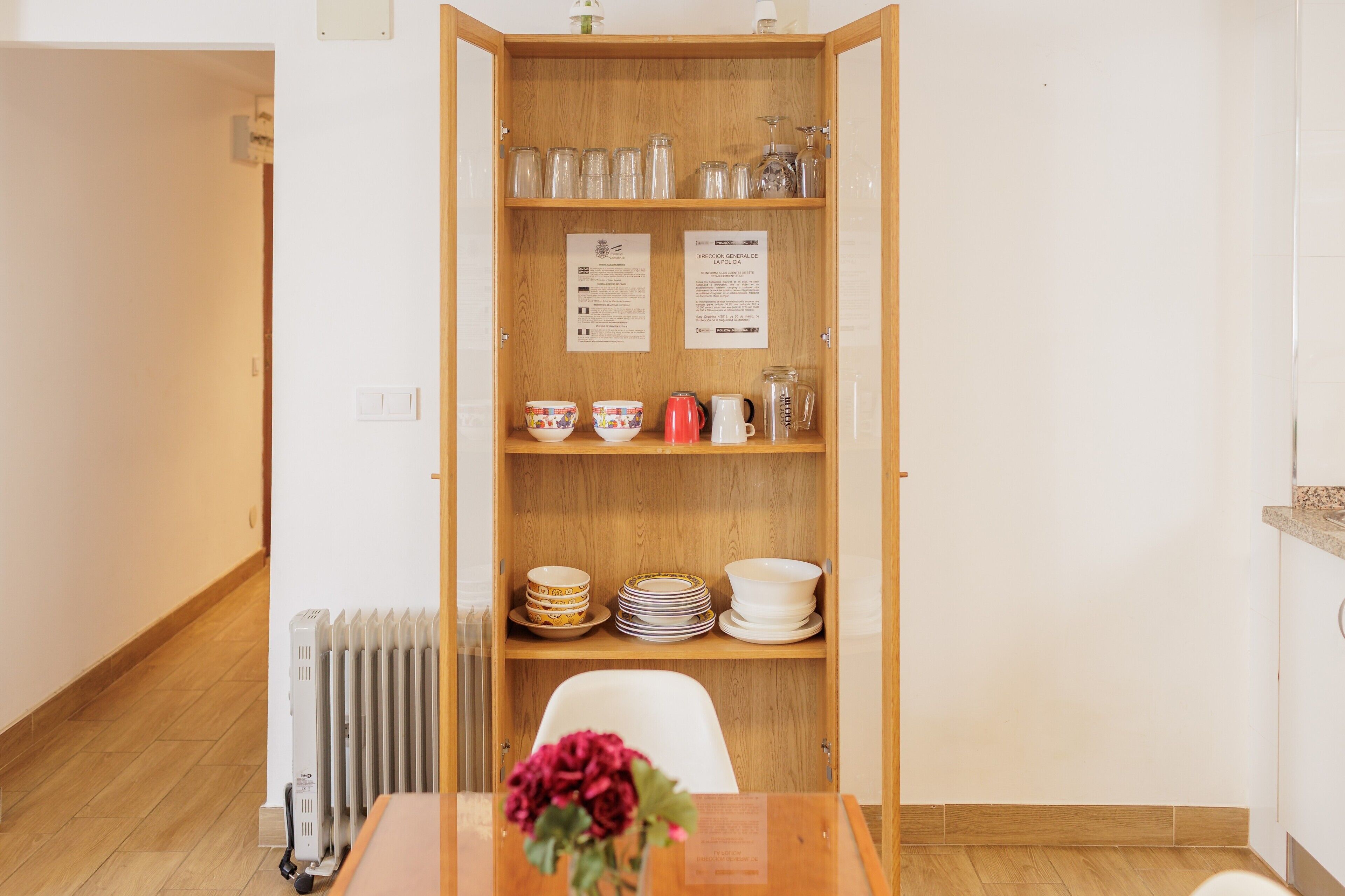 Un coin repas avec un buffet en bois contenant de la verrerie, des bols et des assiettes.