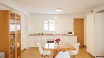 A modern kitchen with white cabinets, a wooden dining table, and white chairs.