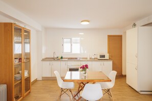 Una cocina moderna con armarios blancos, una mesa de comedor de madera y sillas blancas.