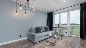 Una sala moderna con un sofá gris, una mesa de centro de vidrio y vistas amplias por grandes ventanales.