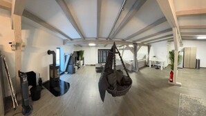 A spacious room with a hanging chair, a bed with a canopy, a desk, and a fire pit.