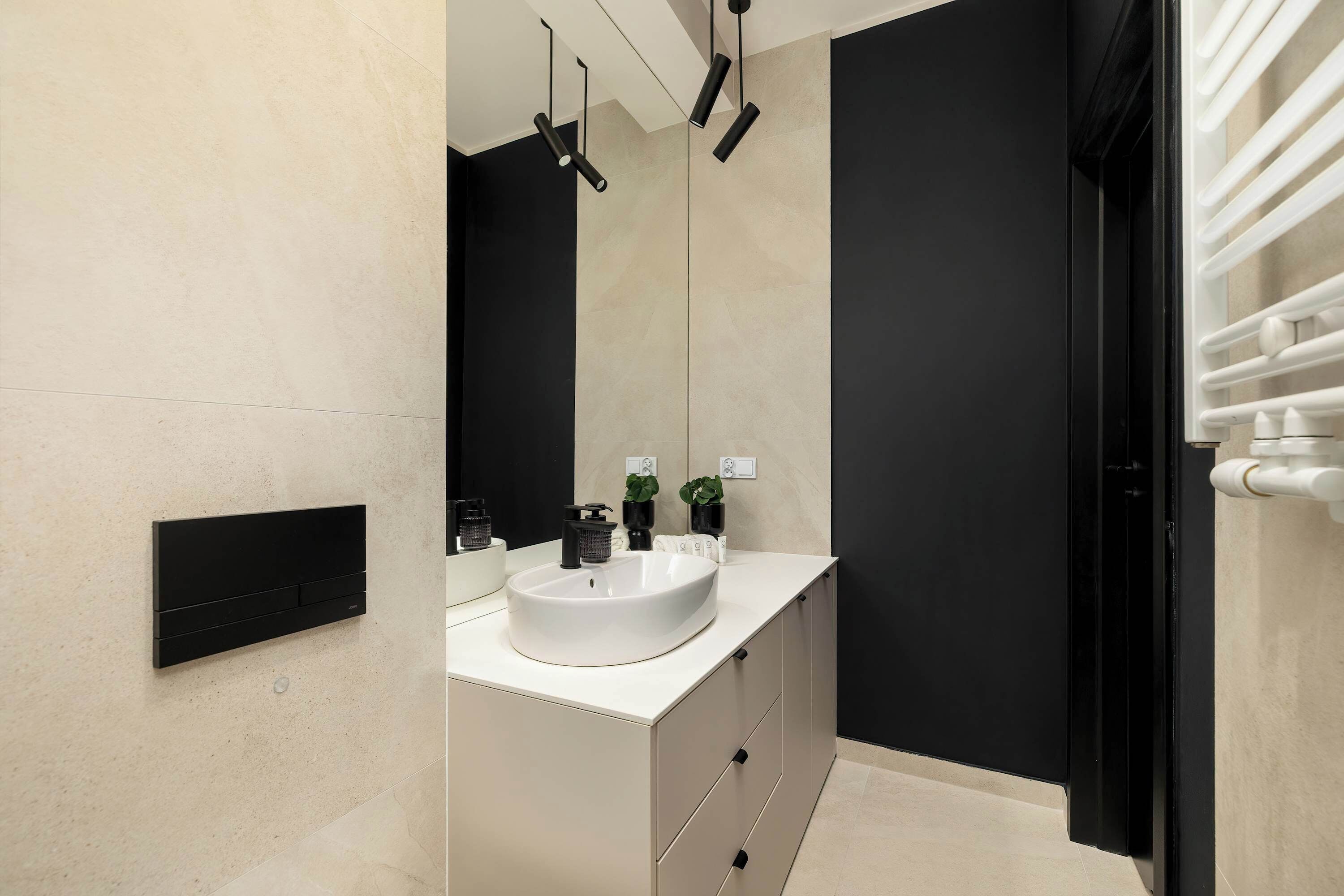 A modern bathroom with a white sink, black fixtures, and a large mirror.