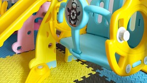 Un área de juegos infantiles con un tobogán, un columpio y una pequeña zona de estar.
