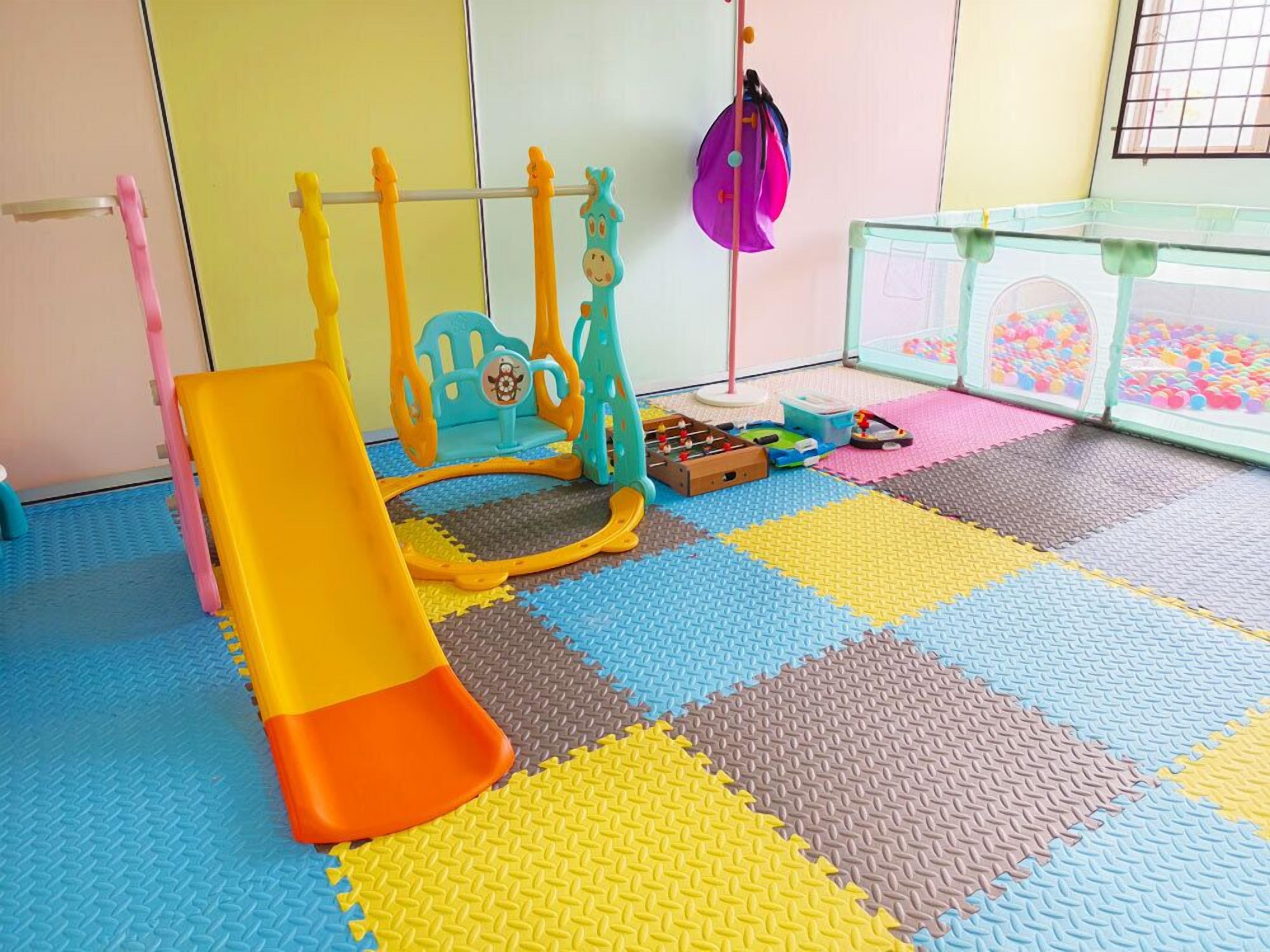 Un espace de jeux avec un toboggan, des structures d’escalade et une piscine à balles.
