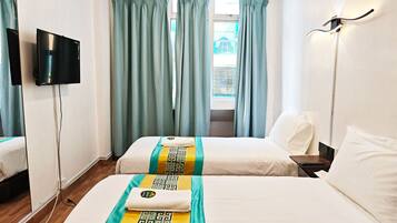 Een hotelkamer met twee bedden, een televisie en een raam met gordijnen.