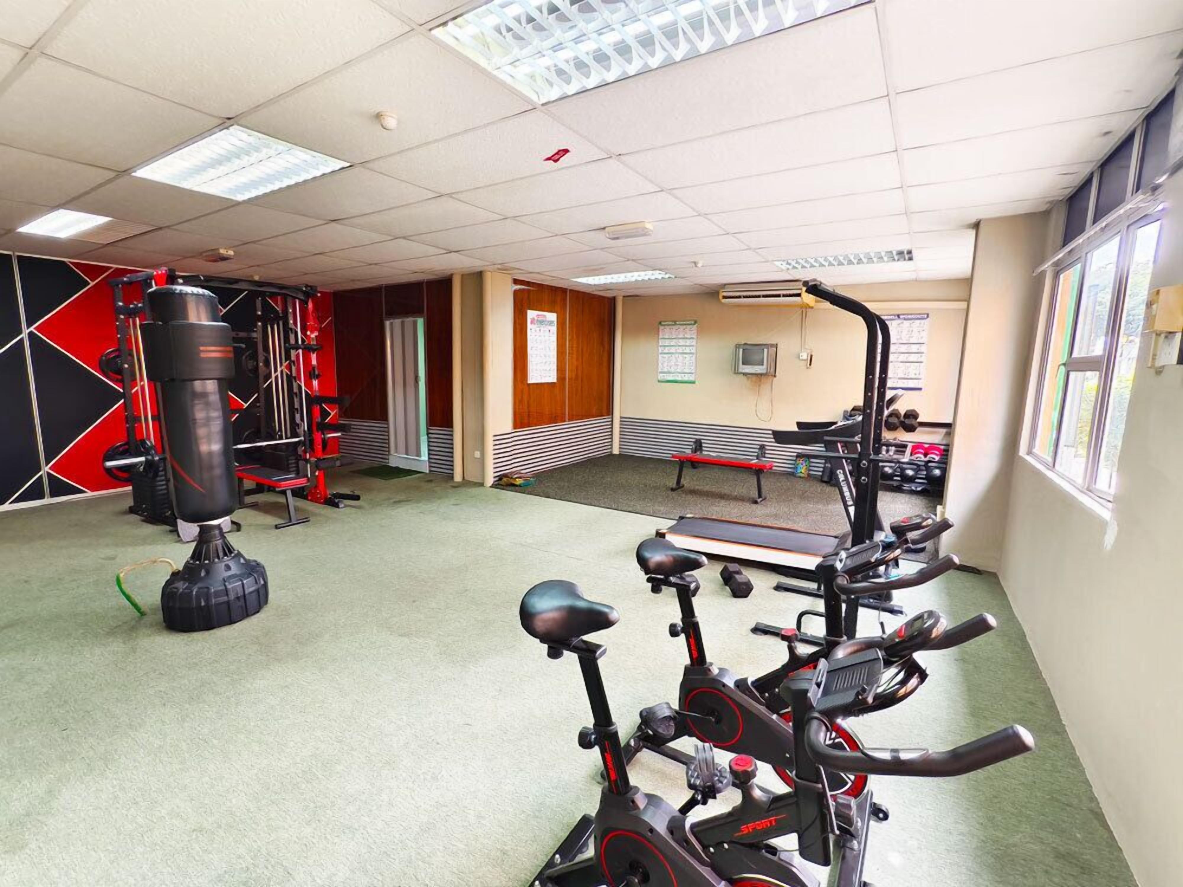 Un gimnasio con equipo de ejercicio, una banca y una cinta de correr.