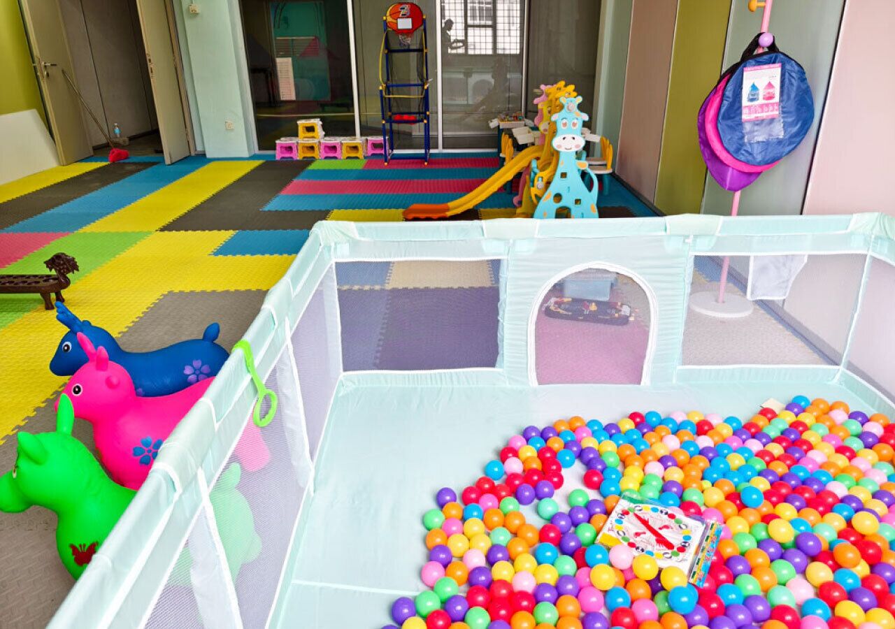 A play area with a ball pit, colorful play structures, and a slide.