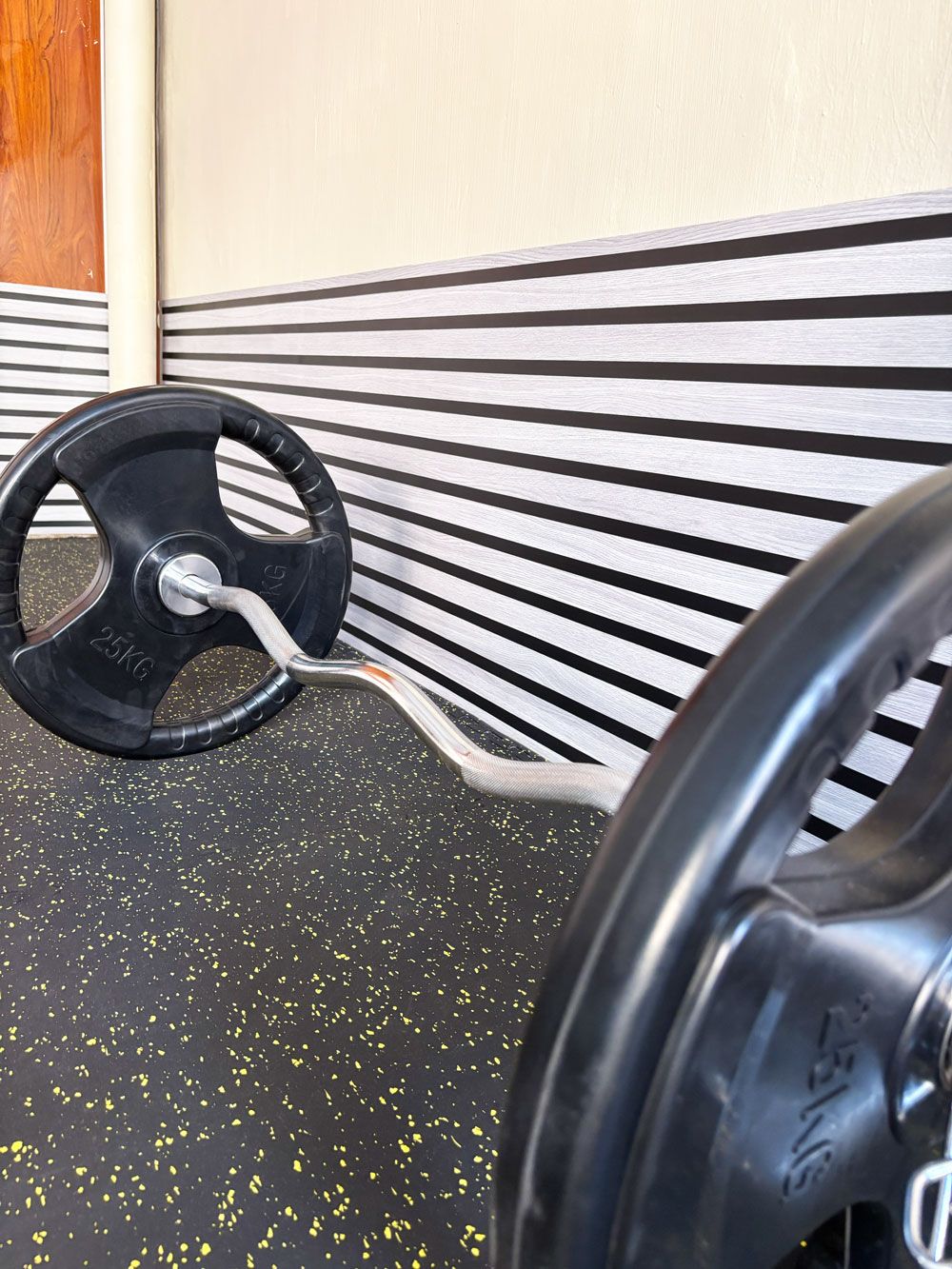 A weight bench with a 25kg barbell and a weight plate.