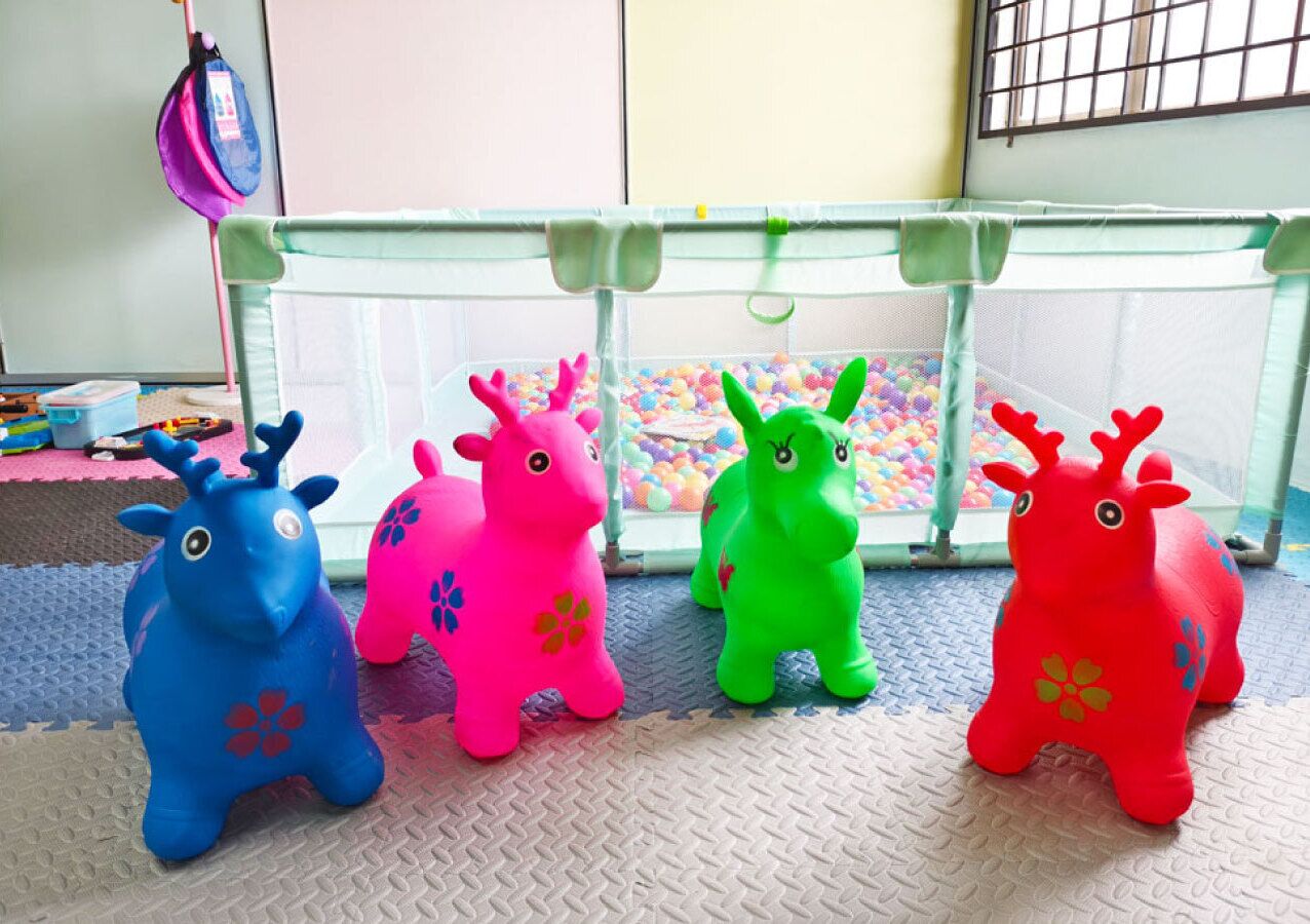 Four colorful plastic toy animals under a playpen.