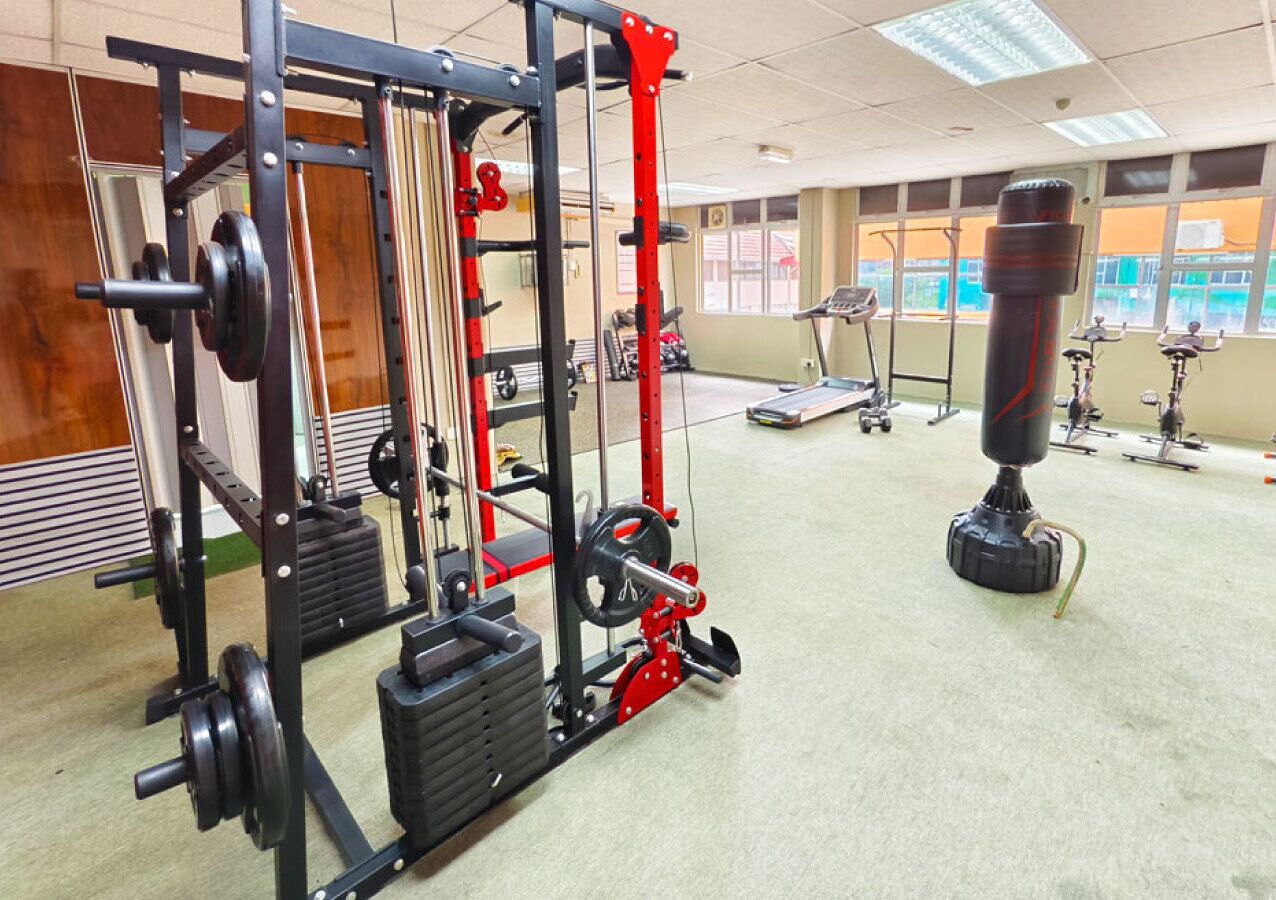 Uma academia com equipamentos de musculação, esteiras e um saco de pancada.