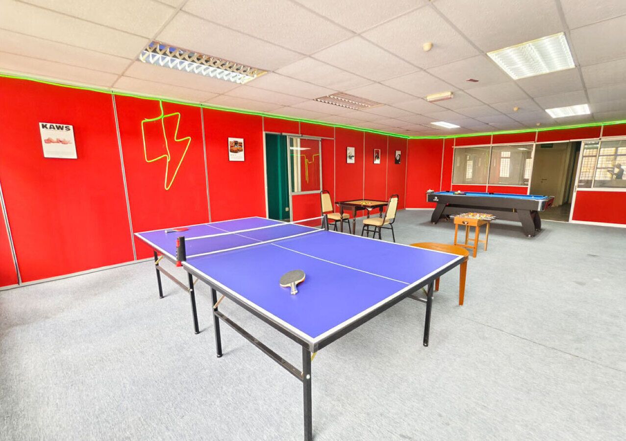 Une pièce équipée d’une table de ping-pong, de chaises et d’une table de billard.