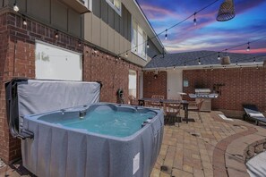 A backyard with a hot tub, outdoor furniture, and a barbecue grill. - Luxury 5BR Getaway w/ Pool, Hot Tub & Cinema (DeSoto)
