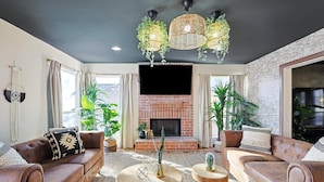 Una sala de estar con chimenea de ladrillo, sofás de cuero y un televisor grande.