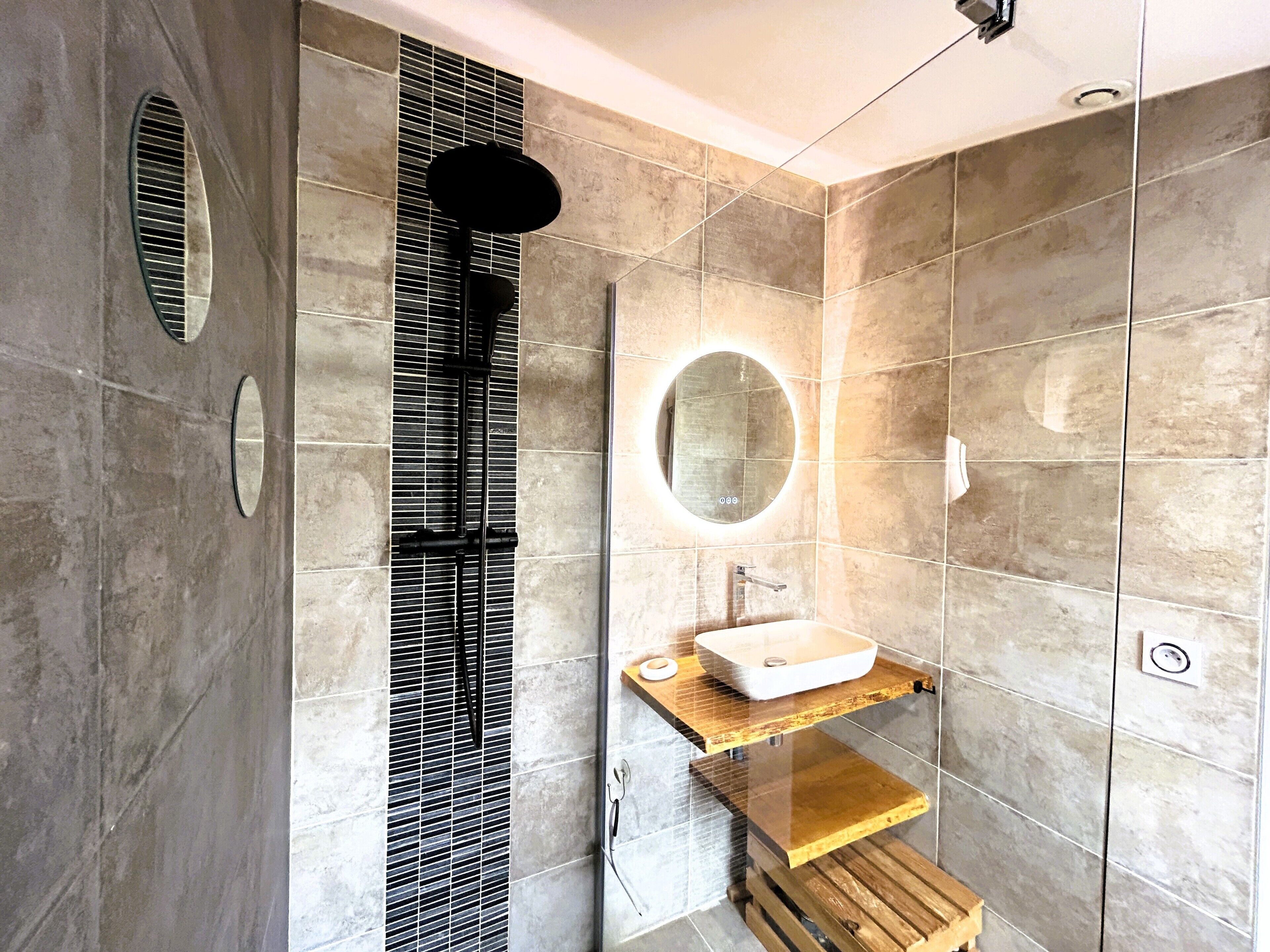 Ein modernes Badezimmer mit großem Spiegel, Waschbecken und Duschbereich.