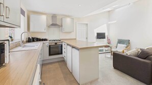 A modern kitchen with a central island, built-in oven, and white cabinetry.