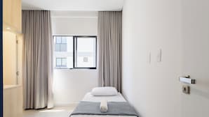 A minimalist hotel room with a bed, curtains, a window, and a door. - Apart w/ Barbecue 800m From the Beach Sre1403 (Itapema)
