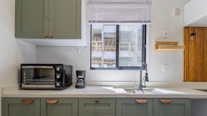 A modern kitchen with a built-in toaster, a coffee maker, and a window with blinds. - Apart w/ Barbecue 800m From the Beach Sre1403 (Itapema)