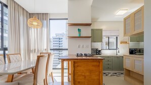 A modern kitchen with a wooden island, built-in appliances, and a view of the city. - Apart w/ Barbecue 800m From the Beach Sre1403 (Itapema)
