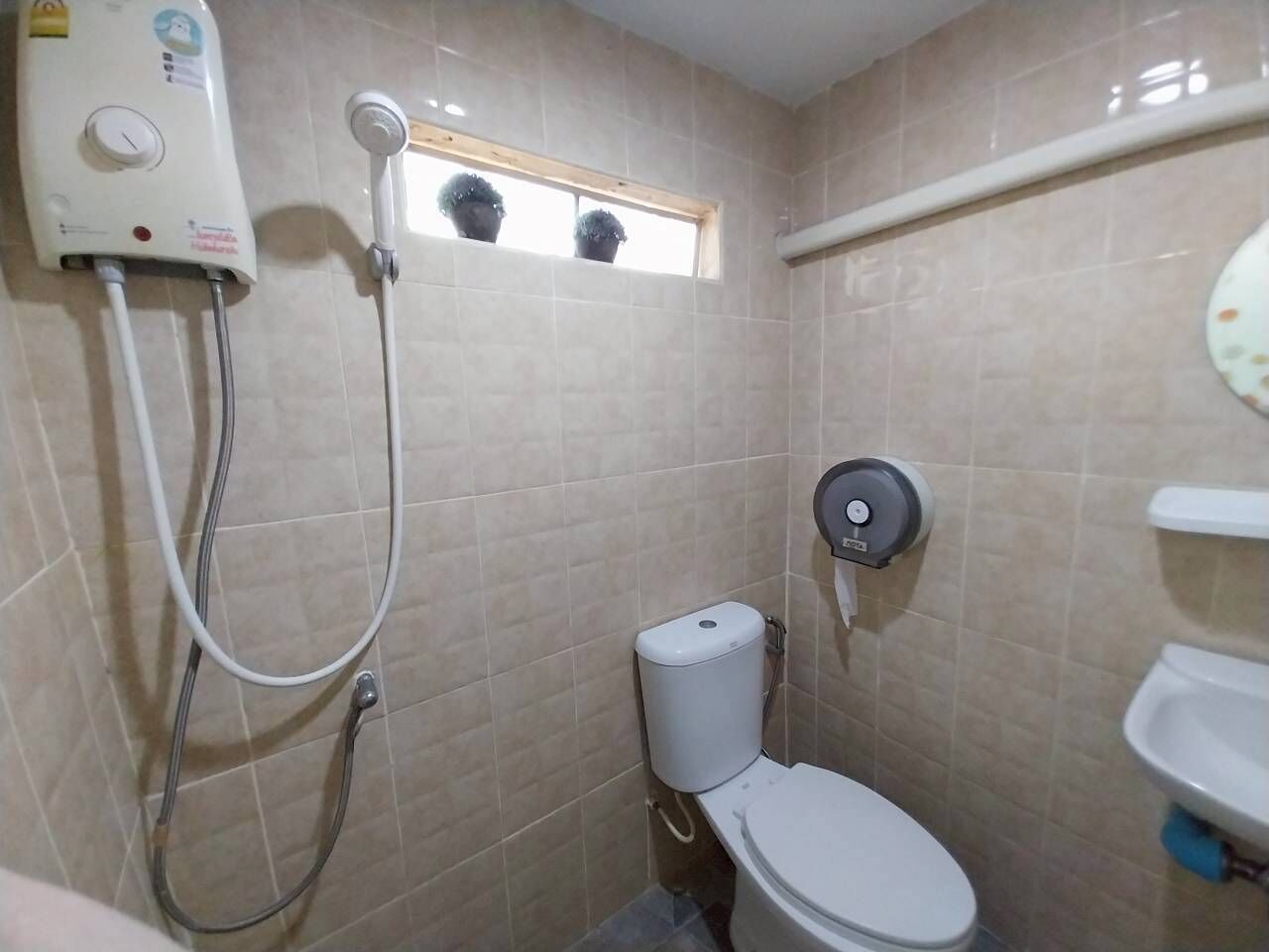 Un baño pequeño con inodoro, un bidé de pared y un cabezal de ducha manual.