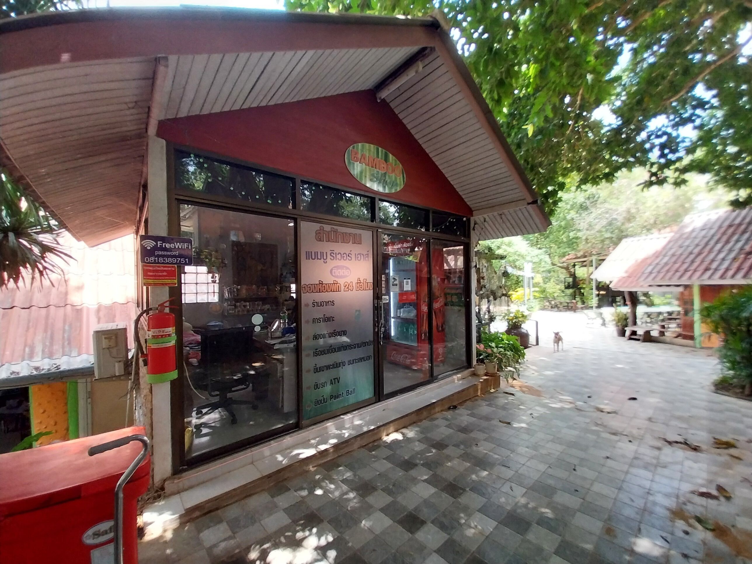 A storefront with a signboard, a fire extinguisher, and a tiled pavement.