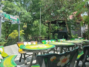 Outdoor seating with tables and chairs, surrounded by lush greenery and trees. - Bamboo River House Kaeng Krachan (Kaeng Krachan)