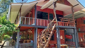 A two-story wooden building with a balcony, a satellite dish, and a staircase.