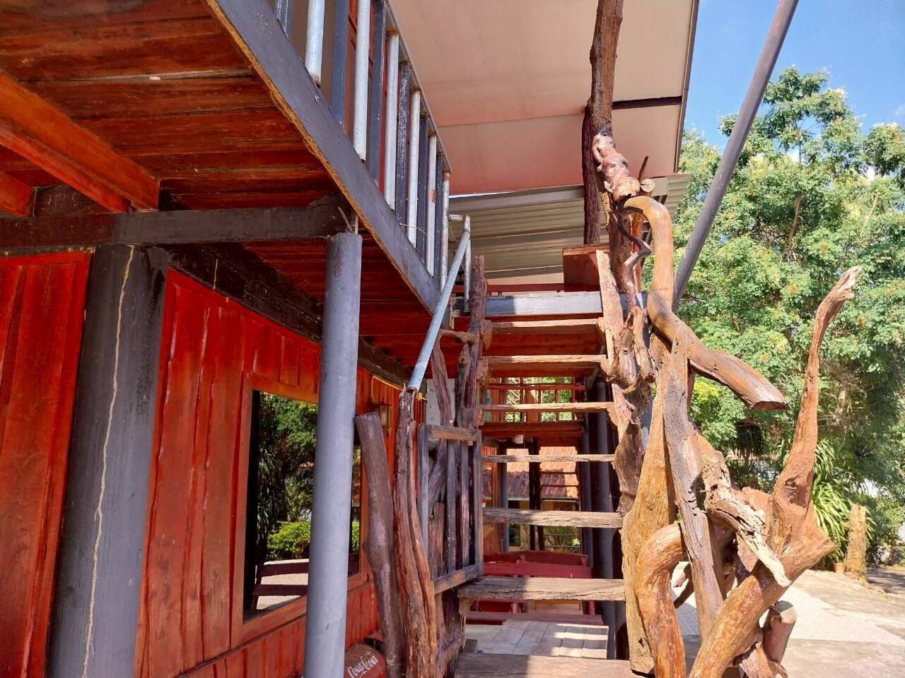 Un escalier en bois au design rustique, menant à un espace abrité d’où l’on peut admirer la verdure.