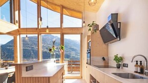 Una cocina moderna con amplios ventanales, armarios de madera y una isla central.