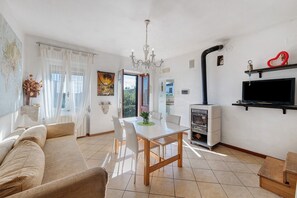 Un salon comprenant un canapé, une table à manger, des chaises, un lustre, un téléviseur et une cheminée.