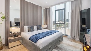 A modern hotel room with a large bed, a desk, and a view of the cityscape. - Vogue | Chaimaa Avenue JVC near Circle Mall (Dubai)