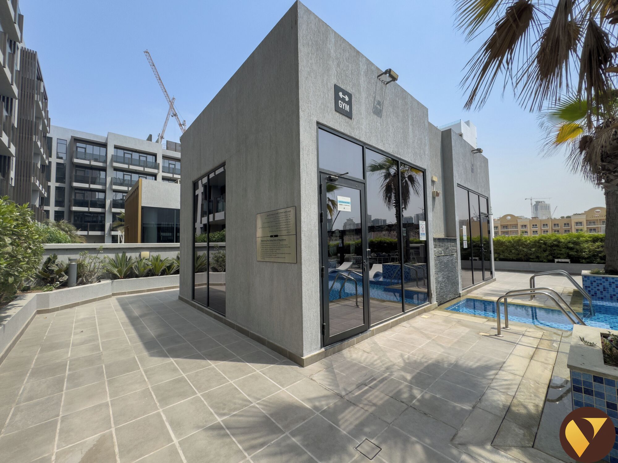 A modern building with a gym sign, a pool, and a clear sky.