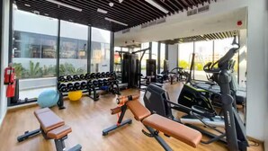 A gym with weightlifting equipment, treadmills, and a bench. - Vogue | Chaimaa Avenue JVC near Circle Mall (Dubai)