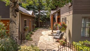 Une terrasse en pierre avec des meubles d’extérieur, une clôture en bois et un bouleau.