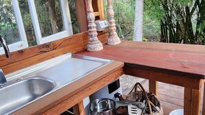 A wooden deck with a sink, two candle holders, and a table with baskets and plates.