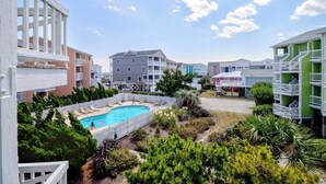 Complejo residencial con piscina rodeada de vegetación y cercas blancas.