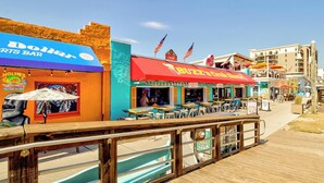 Un paseo marítimo con restaurantes, entre ellos un bar deportivo y una hamburguesería, y una zona de piscina.