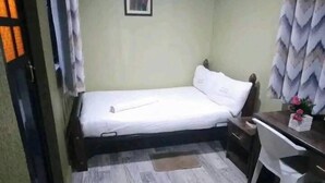 Ein kleines Zimmer mit einem Bett, einem Schreibtisch und einem Stuhl.