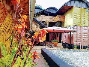A courtyard with a wooden structure, a red umbrella, and a seating area with tables and chairs. - The Posh Inn Kericho (Kericho)