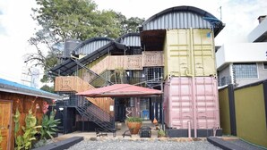 Ein Gebäude mit einzigartigem Design, das Versandcontainer als Wände, eine Treppe und einen überdachten Außenbereich nutzt.