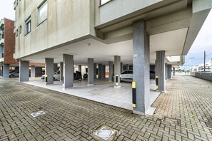 Un área de estacionamiento techada con pilares de hormigón y piso de baldosas.