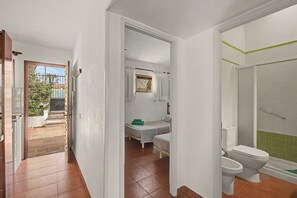 Quarto com cama, uma mesinha e janela.