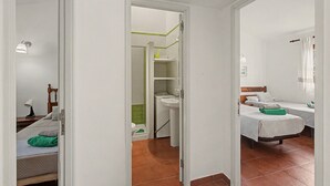Ein Hotelzimmer mit Bett, Nachttisch, Fenster mit Vorhängen und einem Badezimmer mit Toilette und Waschbecken.