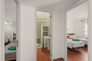 Quarto de hotel com cama, mesa de cabeceira, cortinas na janela e banheiro com vaso sanitário e pia.