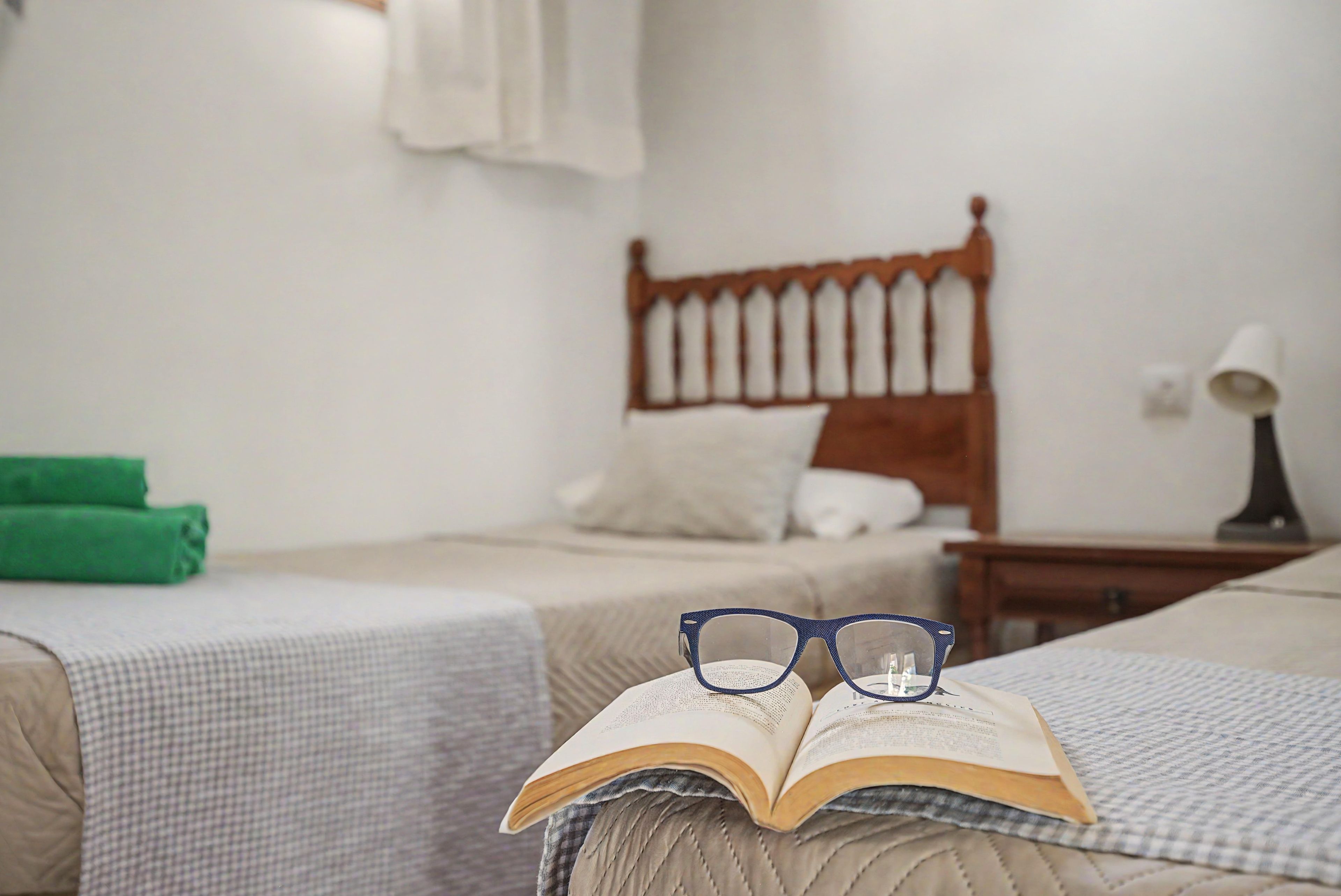 A bedroom with two beds, a nightstand, and a lamp.
