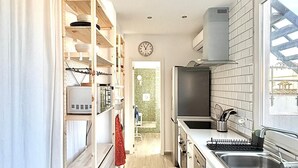 A modern kitchen with white cabinetry, a built-in oven, a stainless steel sink, and a window overlooking the city.